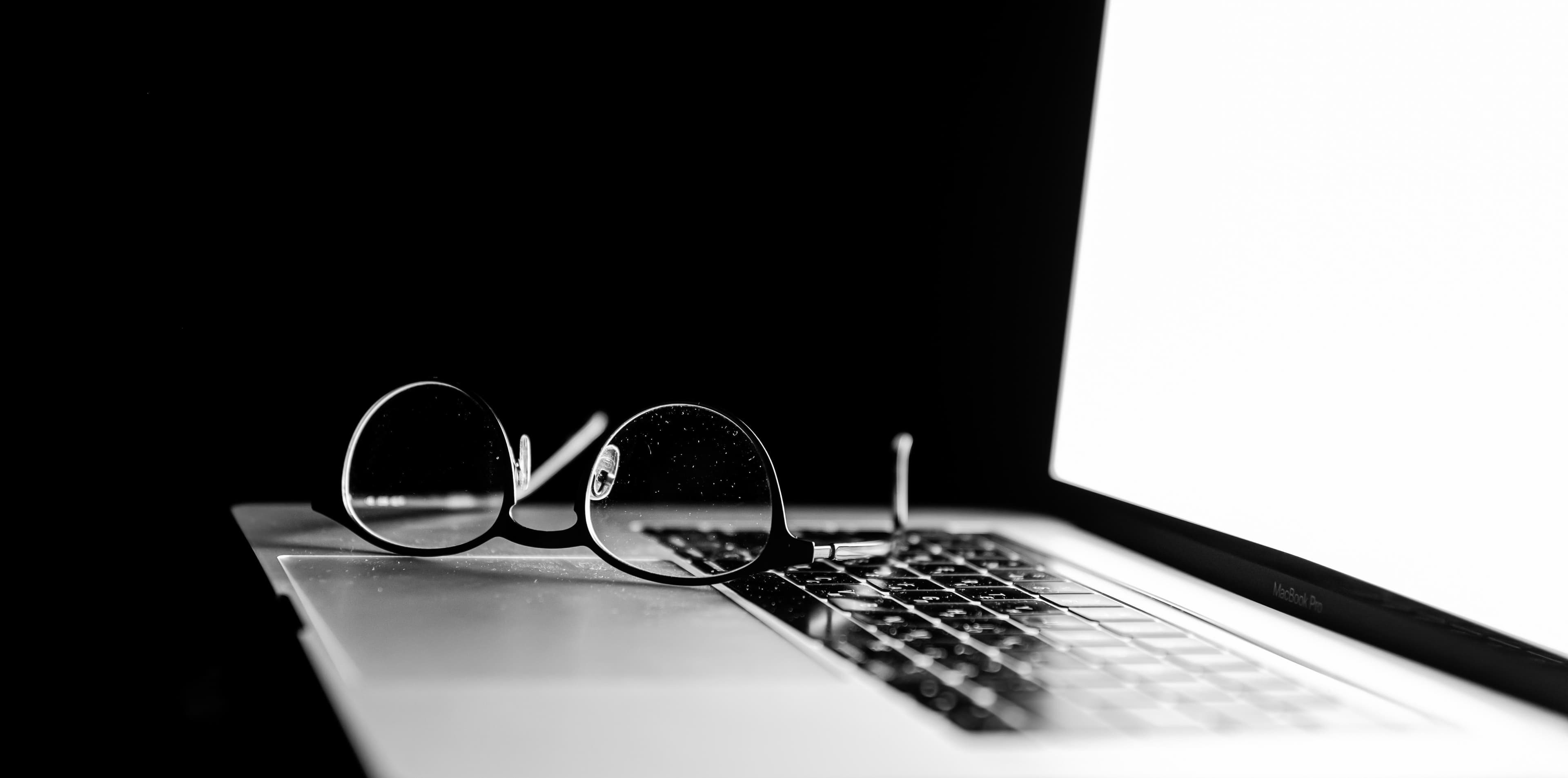 Imagem representando um notebook com um par de óculos em cima